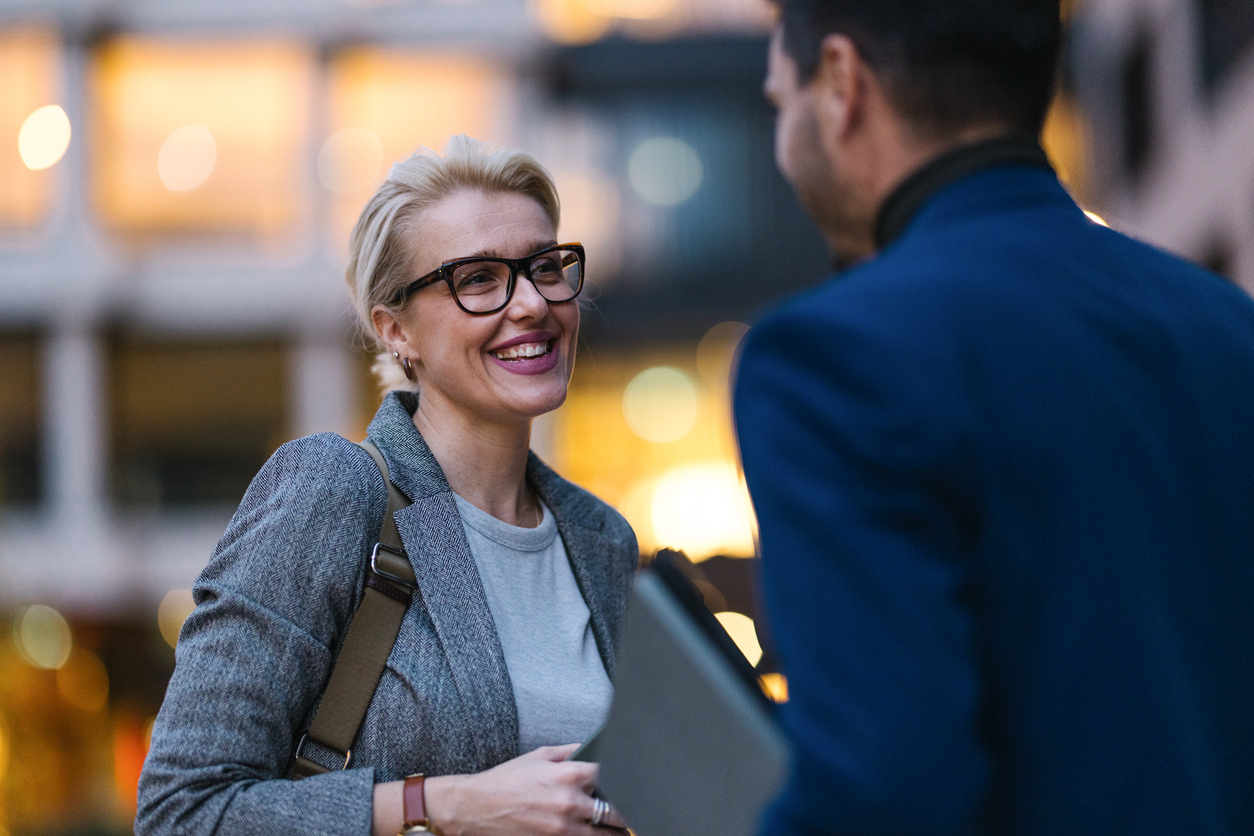 Smiling woman working in financial services, chatting to a colleague.